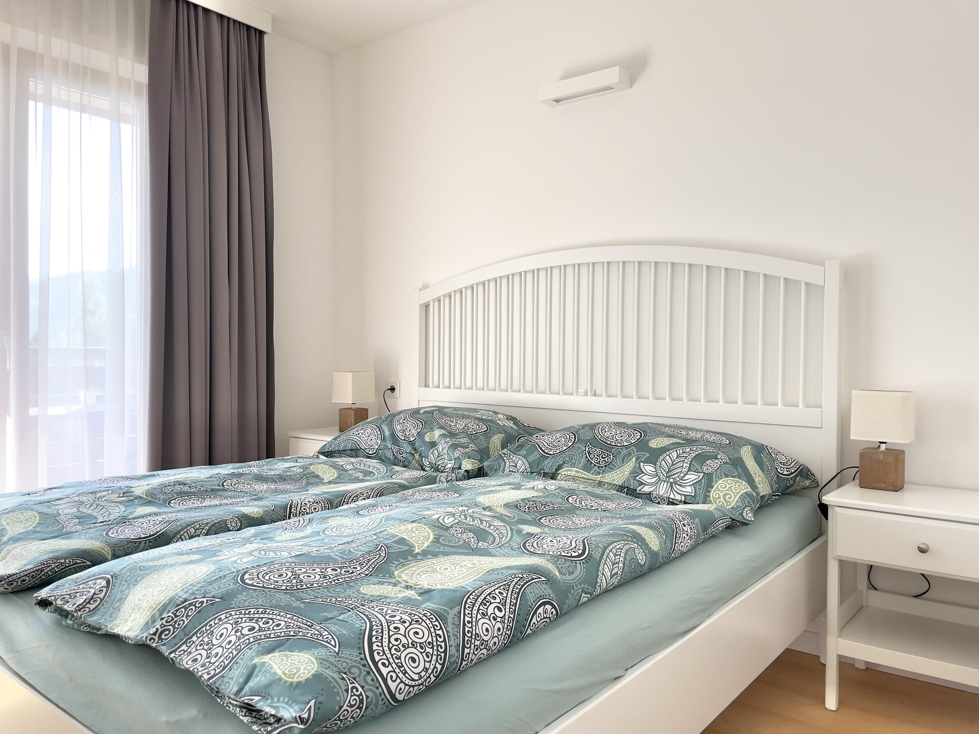 The main bedroom with paisley bedding, a balcony curtain on the left.